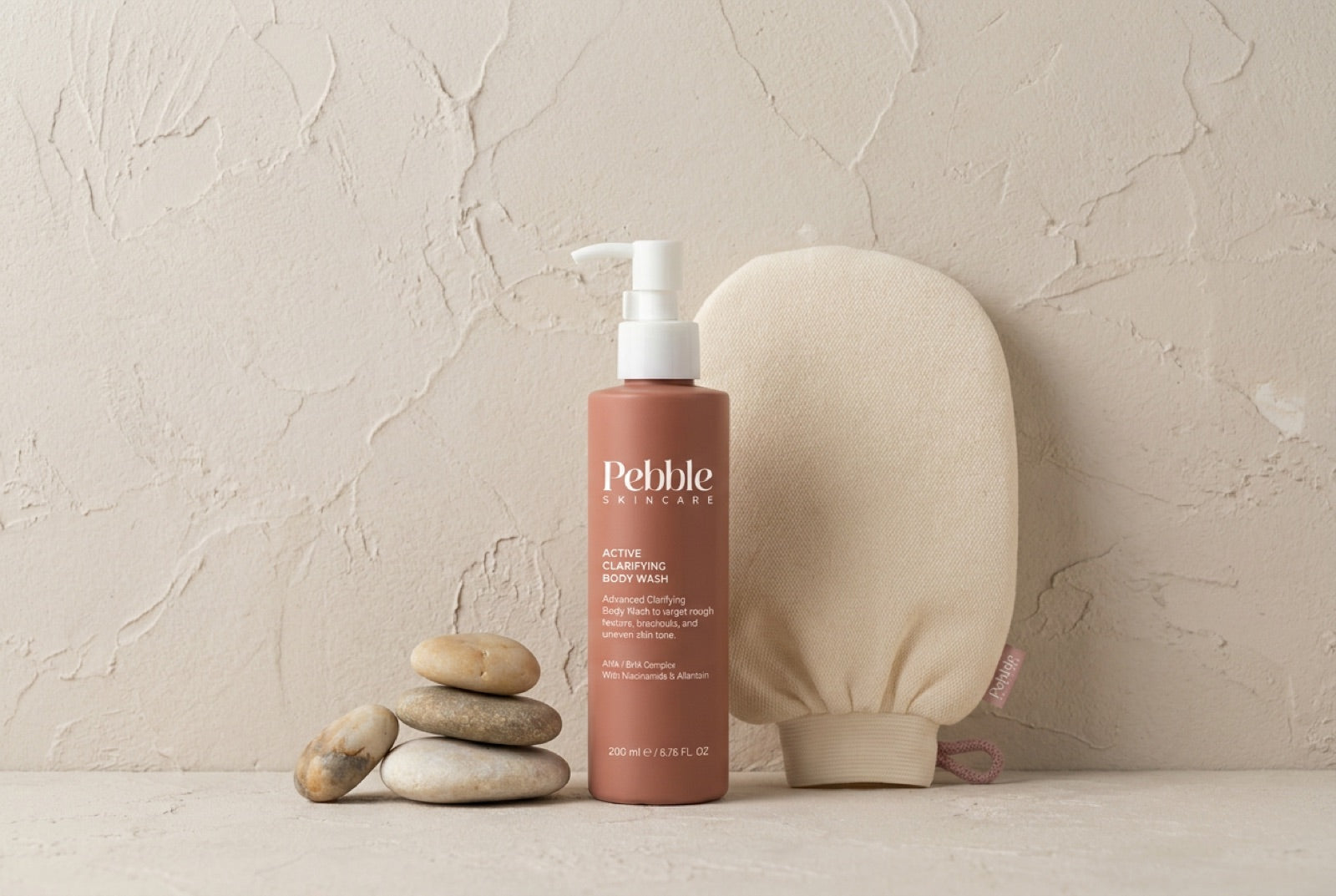 Body wash bottle next to the Pebble exfoliating glove