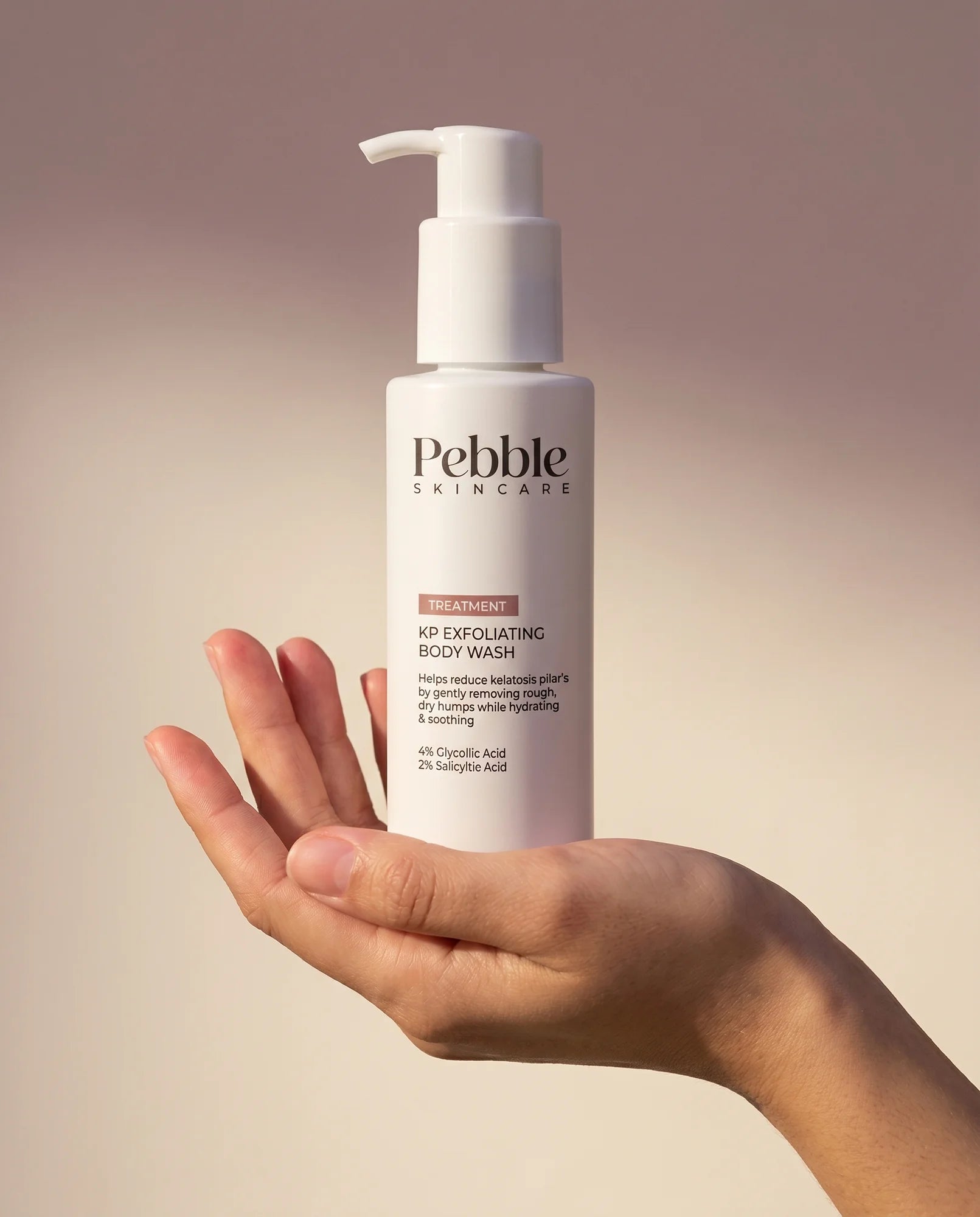 A hand holding the Pebble KP Treatment Wash bottle.
