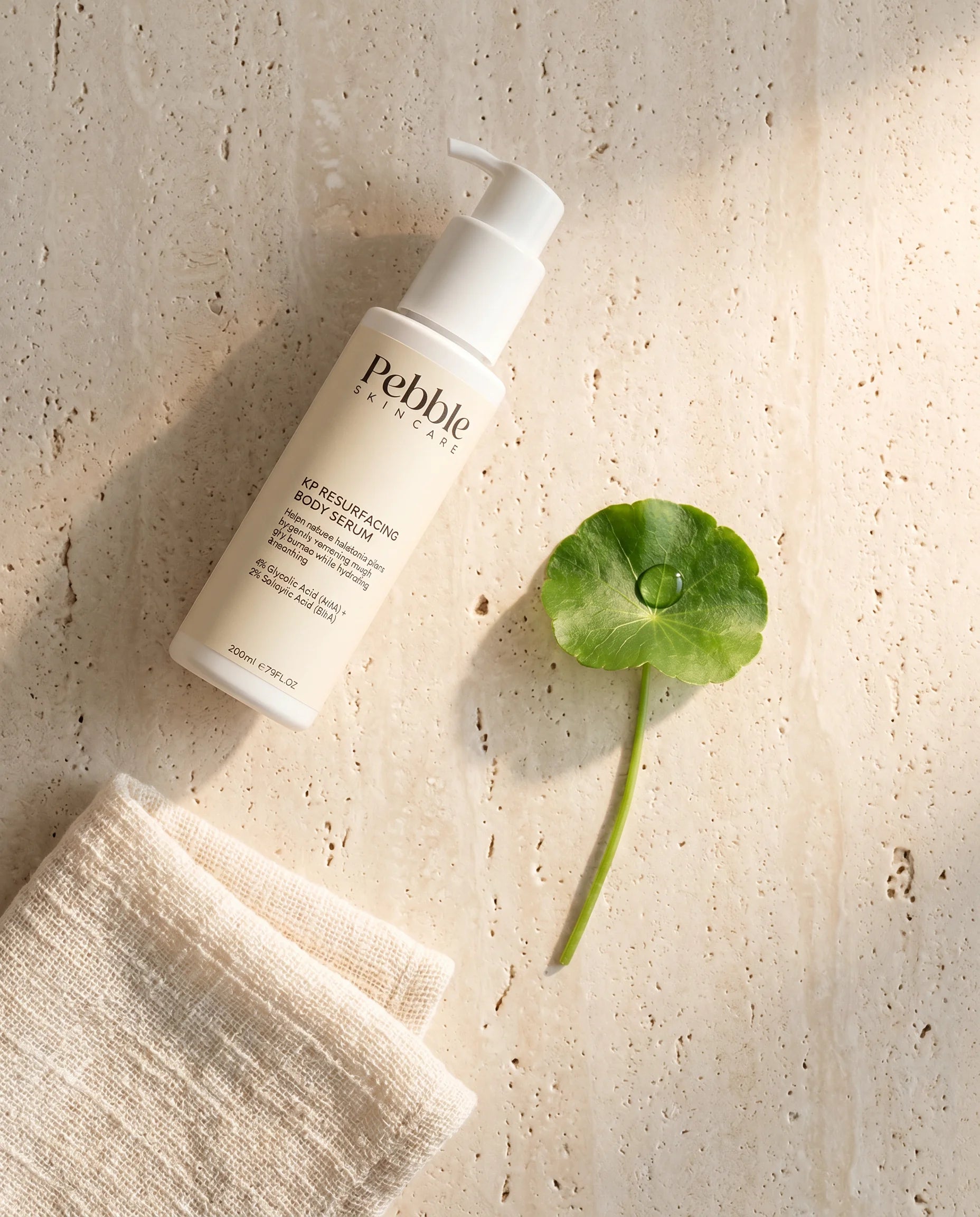 Pebble Serum bottle with cica leaf on cream linen — the Korean ritual.