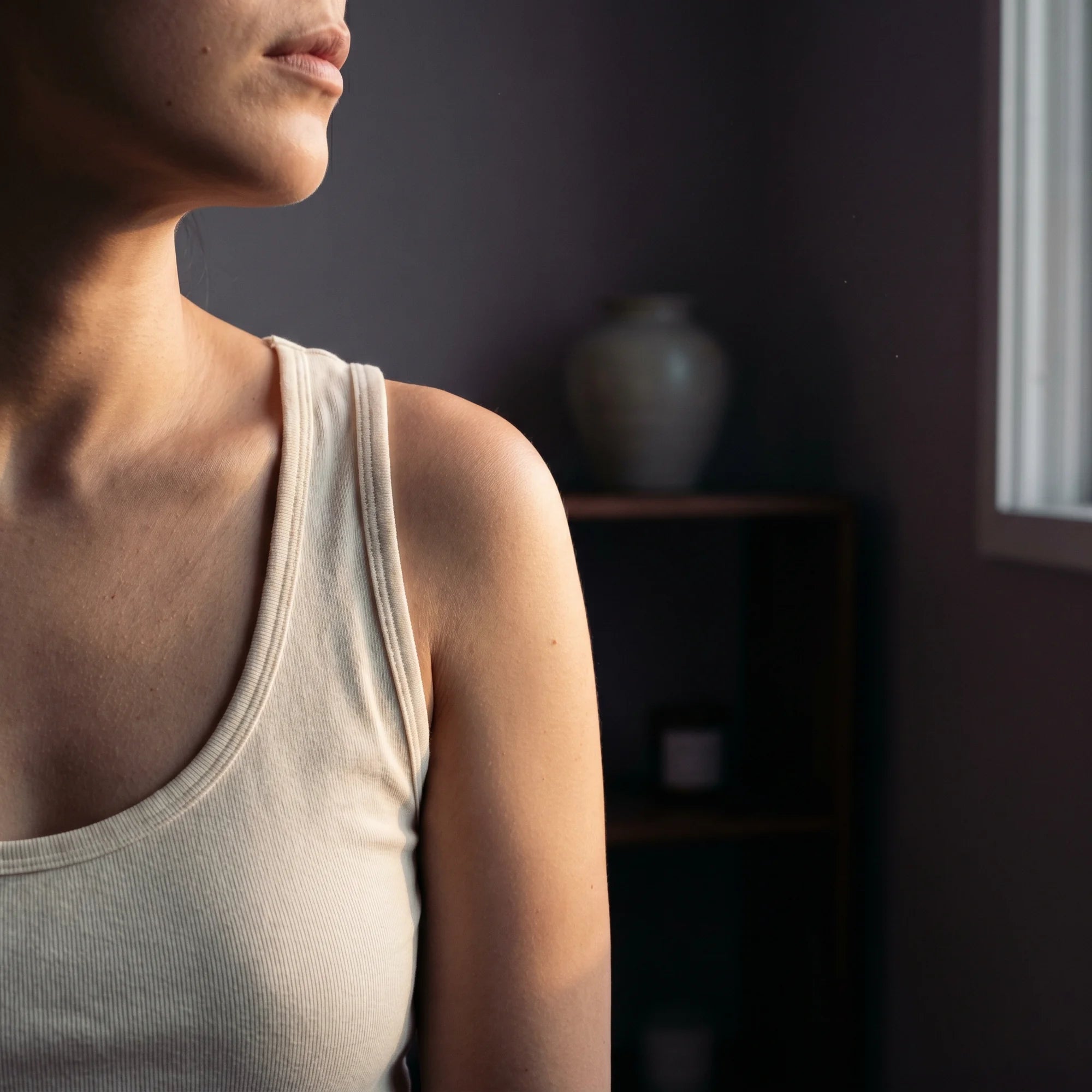 Bare shoulder with soft, even skin against a cream backdrop